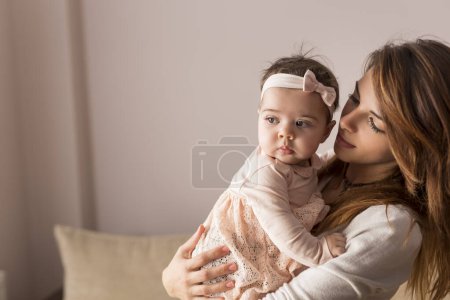 Photo for Young mother holding and hugging her baby girl. Focus on the baby - Royalty Free Image