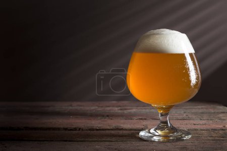 Téléchargez les photos : Verre de bière légère froide non filtrée sur une table de pub rustique en bois - en image libre de droit