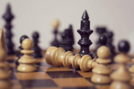 Foto de Primer plano de un tablero de ajedrez de madera y piezas, la reina negra ha vencido a un rey blanco. Enfoque selectivo - Imagen libre de derechos