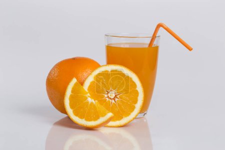 Téléchargez les photos : Plan studio d'un verre de jus d'orange frais et de fruits d'orange isolé sur fond blanc. Focus image empilée - en image libre de droit