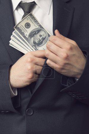Photo for Detail of a man in a suit placing money in his jacket pocket. Selective focus - Royalty Free Image