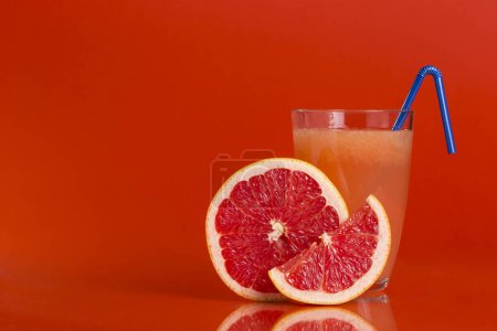 Photo for Glass of fresh grapefruit juice and fruit isolated on red background. Focus stacked image - Royalty Free Image