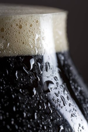 Téléchargez les photos : Détail d'un verre mouillé de bière froide foncée avec un peu de mousse. Concentration sélective - en image libre de droit