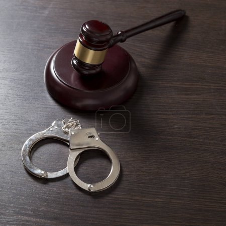 Photo for Close up of a judge gavel and handcuffs in a courtroom. Selective focus - Royalty Free Image