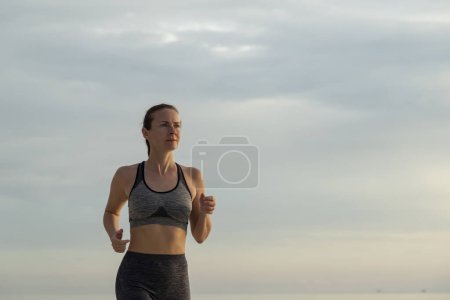 Foto de Mujer activa en ropa deportiva corriendo temprano en la mañana - Imagen libre de derechos