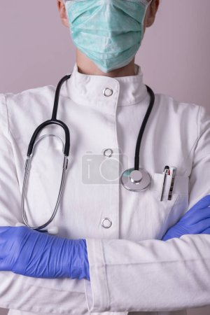 Foto de Detalle de la enfermera en uniforme, con guantes de protección médica y máscara de protección facial; personal médico en lucha contra el brote del virus covid-19 - Imagen libre de derechos