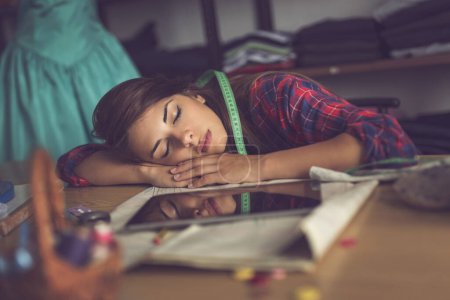 Photo for Young fashion designer fell asleep in her fashion atelier while working overtime - Royalty Free Image
