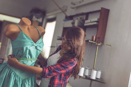 Photo for Young fashion designer working on a new dress in her atelier, taking measures with measuring tape - Royalty Free Image