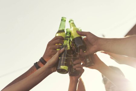 Téléchargez les photos : Détail des mains tenant des bouteilles de bière, portant un toast et profitant des chaudes journées d'été. Focus sélectif sur la main féminine à gauche - en image libre de droit