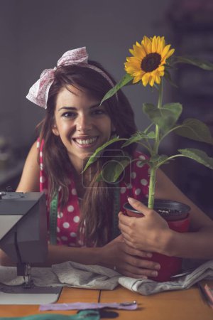 Photo for Beautiful young seamstress sitting and taking a break in her workshop, relaxed and joyful - Royalty Free Image