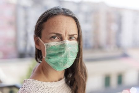 Photo for Portrait of young woman wearing surgical mask outdoors as part of coronavirus protection and prevention protocols - Royalty Free Image