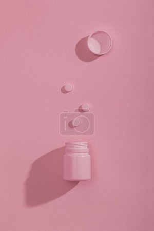Photo for Top view of a spilled bottle of pills isolated on pink colored background with copy space; - Royalty Free Image