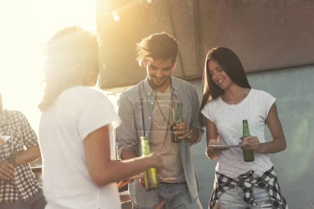 Photo for Group of young friends having fun at rooftop party, making barbecue and enjoying hot summer days. Focus on the girl on the right - Royalty Free Image