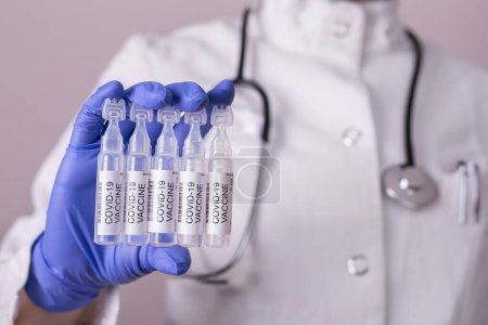 Téléchargez les photos : Immunologue tenant des flacons de vaccin covid-19 ; médecin tenant de nouveaux vaccins contre le corronavirus - en image libre de droit