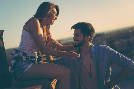 Téléchargez les photos : Couple amoureux s'amuser sur un toit de bâtiment, profiter d'un magnifique coucher de soleil d'été sur la ville - en image libre de droit