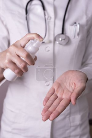 Foto de Detalle del médico pulverizando las manos con aerosol de desinfección de manos como parte del protocolo de prevención de infecciones intrahospitalarias; personal médico en lucha contra el brote del virus covis-19 - Imagen libre de derechos