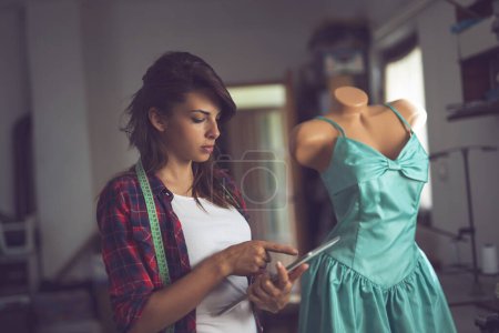 Photo for Young fashion designer working on a new dress models in her atelier - Royalty Free Image