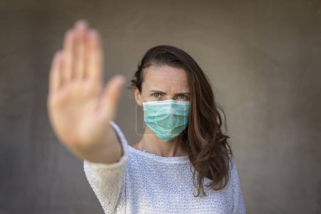 Foto de Retrato de una mujer con máscara de protección facial y señal de stop gestual; prevención del coronavirus y concepto de distanciamiento social - Imagen libre de derechos