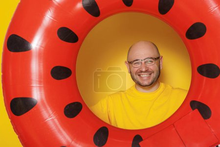 Foto de Hombre alegre sosteniendo anillo de natación de sandía inflable sobre fondo de color amarillo - vacaciones de verano y concepto de viaje - Imagen libre de derechos