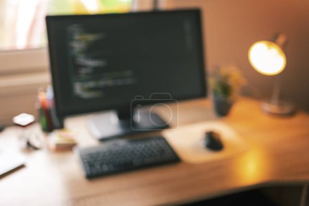 Photo for Desktop computer turned on with code on screen placed on empty desk in software developer home office - Royalty Free Image