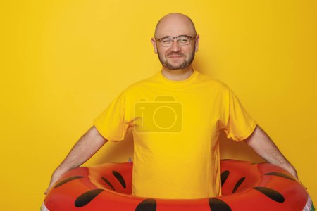 Téléchargez les photos : Joyeux homme tenant anneau gonflable de natation de pastèque sur fond jaune vacances d'été et concept de voyage - en image libre de droit