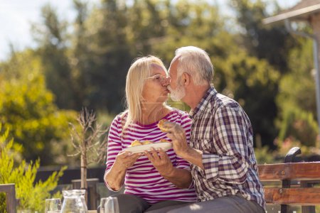 Foto de Feliz pareja de ancianos disfrutando de su tiempo juntos desayunando al aire libre en el patio trasero de su casa - Imagen libre de derechos