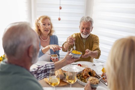 Foto de Dos parejas mayores teniendo Acción de Gracias juntas en casa, comiendo, bebiendo, riendo y divirtiéndose - Imagen libre de derechos