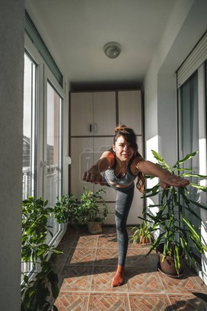 Téléchargez les photos : Femme en vêtements de sport faisant de l'exercice à la maison le matin, se détendre tout en faisant du yoga - en image libre de droit