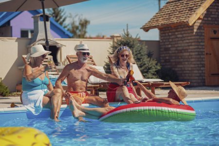 Foto de Grupo de personas mayores alegres relajarse y tomar el sol en la piscina mientras que en unas vacaciones de verano, hacer un brindis, beber cócteles y cerveza y divertirse - Imagen libre de derechos