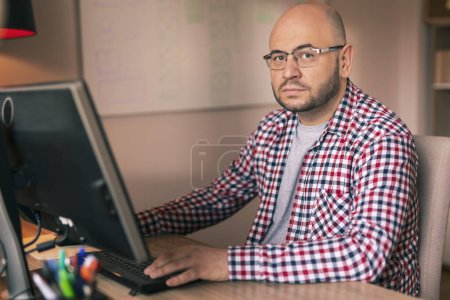 Photo for Graphic designer working on new mobile phone app development; male freelancer working in a home office - Royalty Free Image