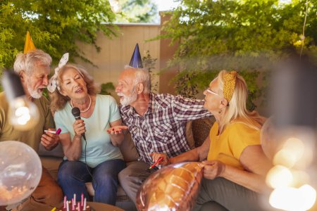 Foto de Grupo de alegres amigos mayores cantando y divirtiéndose en la fiesta de cumpleaños de karaoke - Imagen libre de derechos