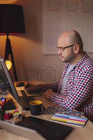Foto de Diseñador web que trabaja desde casa, sentado en su escritorio y dibujando con almohadilla de dibujo - Imagen libre de derechos