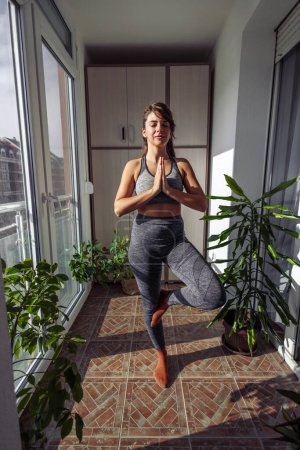Téléchargez les photos : Femme en vêtements de sport relaxant tout en faisant séance de yoga matin à la maison - en image libre de droit