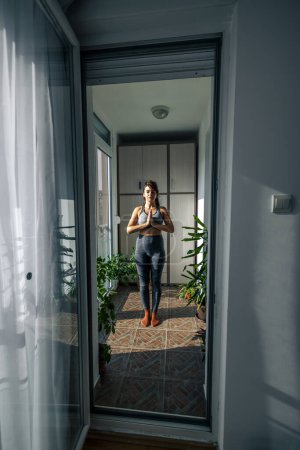 Photo for Woman in sportswear exercising at home in the morning, relaxing while doing yoga - Royalty Free Image