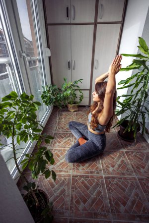 Téléchargez les photos : Belle jeune femme relaxante tout en faisant une séance de méditation à la maison le matin - en image libre de droit