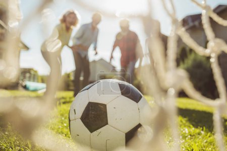 Photo for Group of active senior people having fun playing football on the lawn in the backyard, enjoying sunny summer day outdoors, celebrating after scoring a goal - Royalty Free Image