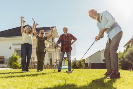 Photo for Elderly people having fun playing mini golf at the backyard lawn, spending sunny summer day outdoors - Royalty Free Image
