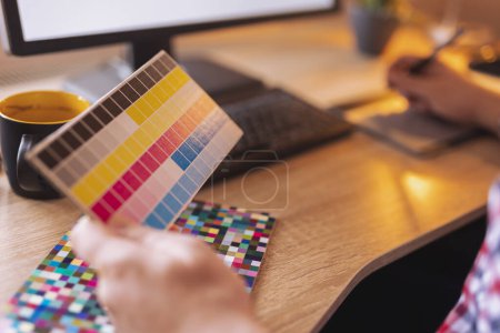 Téléchargez les photos : Détail de la main du concepteur tenant la palette de couleurs et le dessin à l'aide d'une carte graphique tout en travaillant dans un bureau à domicile - en image libre de droit
