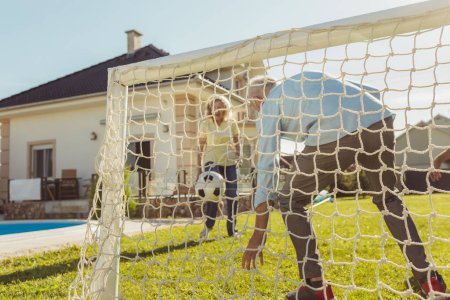 Foto de Personas mayores activas que se divierten jugando fútbol en el césped en el patio trasero, disfrutando de un soleado día de verano al aire libre, celebrando después de marcar un gol - Imagen libre de derechos