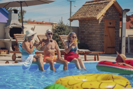 Photo for Group of cheerful senior people relaxing and sunbathing by the swimming pool while on a summer vacation, drinking cocktails and beer and having fun - Royalty Free Image