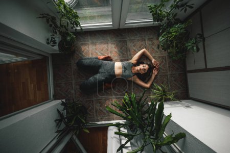 Foto de Vista superior de la hermosa mujer joven relajándose mientras hace yoga en casa por la mañana - Imagen libre de derechos