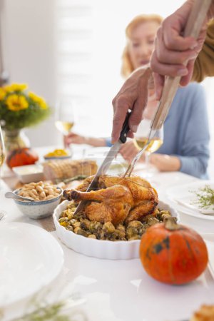 Foto de Primer plano de las manos masculinas cortando el pollo y la mesa para que la gente celebre el Día de Acción de Gracias y celebre la cena en casa - Imagen libre de derechos