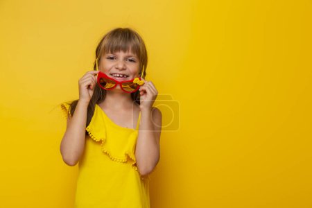 Foto de Retrato de una hermosa niña con gafas de sol, preparándose para las vacaciones de verano, aislado sobre fondo de color amarillo - Imagen libre de derechos