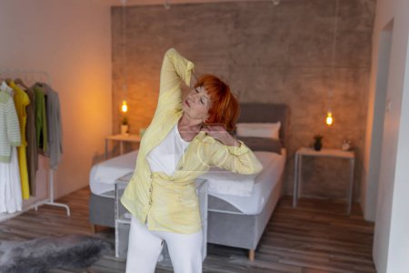 Téléchargez les photos : Femme âgée active faisant de l'entraînement de yoga à la maison concept de mode de vie sain - en image libre de droit