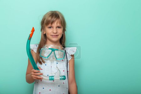 Photo for Excited little girl getting ready for beach summer vacation, holding snorkeling mask, isolated on mint colored background - Royalty Free Image