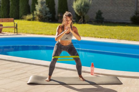 Téléchargez les photos : Fit femme exerçant près de la piscine, faire des squats - en image libre de droit