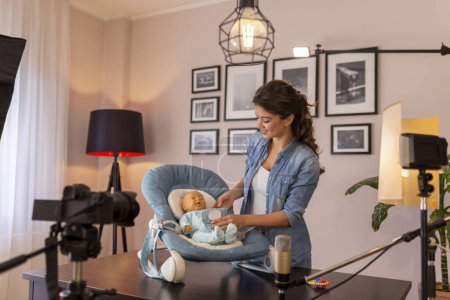 Téléchargez les photos : Vlogger faire une vidéo sur l'utilisation du siège oscillant pour bébé nouveau-né dans le cadre de cours de naissance en ligne - en image libre de droit