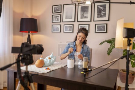 Photo for Female vlogger recording video about newborn baby bottle feeding and baby formula milk preparation as part of online prenatal classes - Royalty Free Image