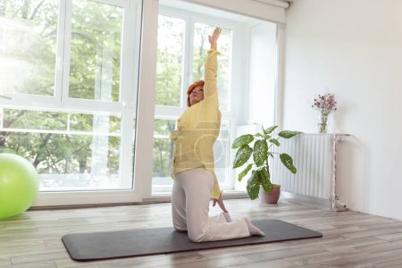Foto de Mujer mayor practicando yoga en casa; estilo de vida saludable y activo del concepto de personas mayores - Imagen libre de derechos