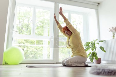 Photo for Senior woman doing yoga practice at home; healthy and active lifestyle of elderly people concept - Royalty Free Image